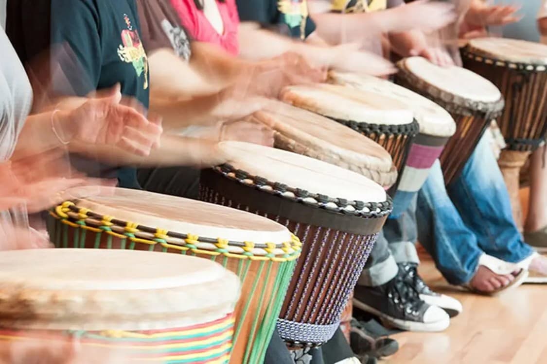 A group drumming together on djembes during a culture-exchange session.